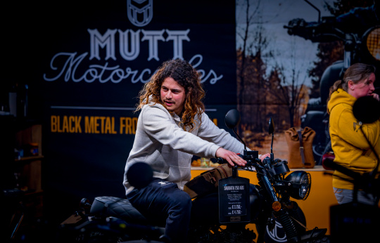 Man probeert motor uit in Mutt Motorcycles stand