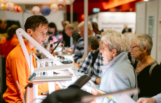 Foto van een standhouder in gesprek met een bezoeker