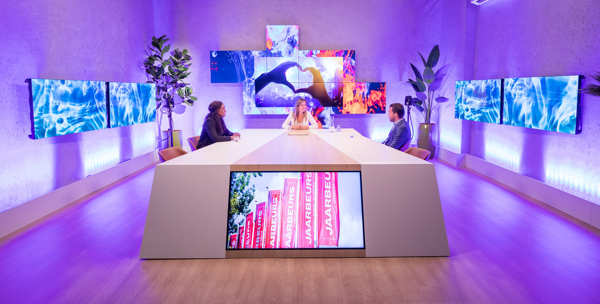 3 mensen zitten aan tafel in een studio